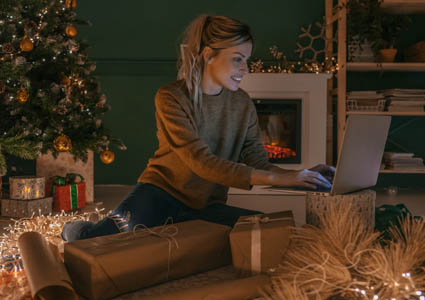 woman sitting in front of her Christmas tree on laptop